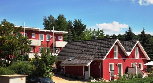 a red house with a black roof in front of houses at PONTUS Ferienwohnung FeWo4 in Zislow