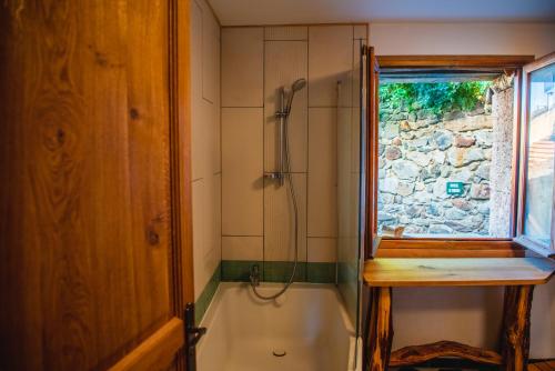 een badkamer met een bad en een douche met een raam bij The Dragon Barn - Grenier in Ascou