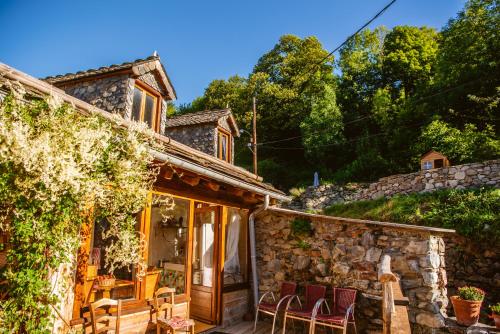 una casa de piedra con patio y sillas en The Dragon Barn - Grenier, en Ascou