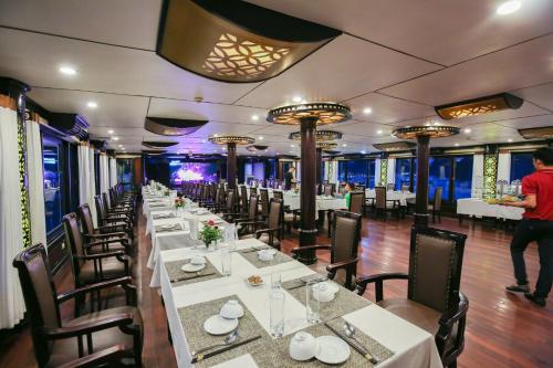 a dining room with long tables and chairs and a man standing in the background at Starlight Cruise in Ha Long