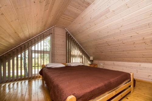 um quarto com uma cama num quarto de madeira em Mediniai nameliai Žibų 99 em Šventoji