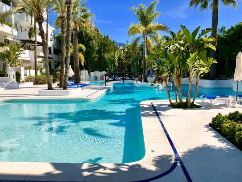 a swimming pool with palm trees in a resort at Luxury apartment in La Isla, Puerto Banus in Marbella