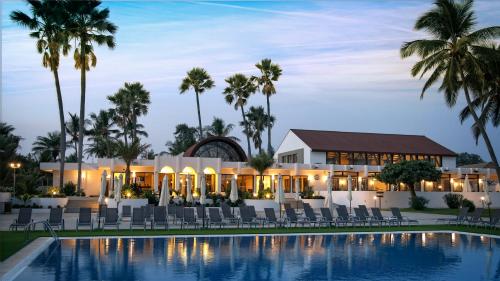 a resort with a pool and chairs and palm trees at Sunbeach Hotel & Resort in Bakau