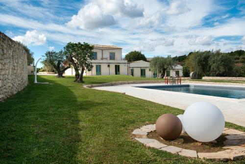 una casa con piscina y 2 huevos en el césped en Relais Terre di Romanello en Noto