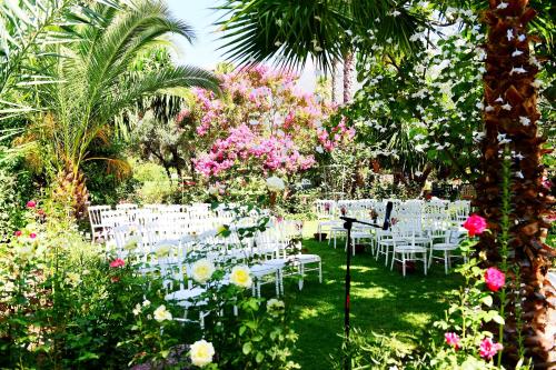 a garden with white chairs and tables and flowers at Domaine de la Roseraie Resort in Ouirgane