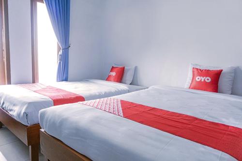 twee bedden naast elkaar in een kamer bij SUPER OYO 1565 Hotel Homiko in Pacitan