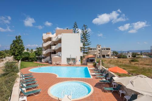 um resort com uma piscina e cadeiras e um edifício em Hermes Hotel em Kissamos