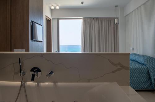 a bathroom with a bath tub with a mirror at Mandali Hotel in Protaras