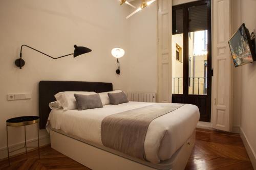 een slaapkamer met een bed, een lamp en een raam bij SY Fuencarral in Madrid