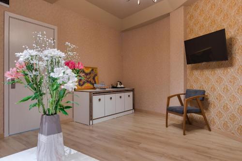 a living room with a vase of flowers and a tv at Savaneti Eco Hotel in Tʼelavi