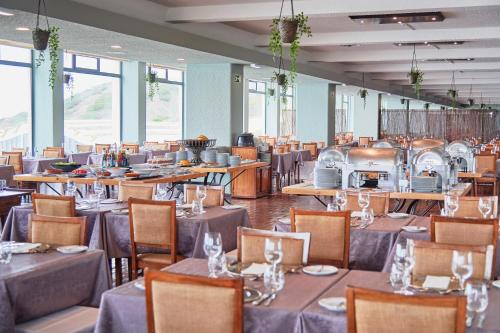 un comedor con mesas, sillas y ventanas en Hotel Golf Mar, en Maceira