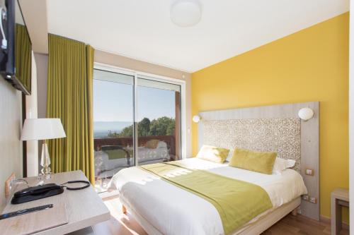 - une chambre avec un grand lit et une grande fenêtre dans l'établissement Hôtel-Restaurant Bois Joly, à Crozet