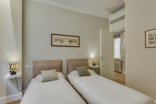 2 łóżka w pokoju z białymi ścianami w obiekcie Sophisticated Home we Florencji