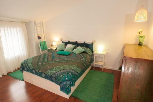 ein Schlafzimmer mit einem Bett mit einer grünen Bettdecke in der Unterkunft La Postoca in Viavélez