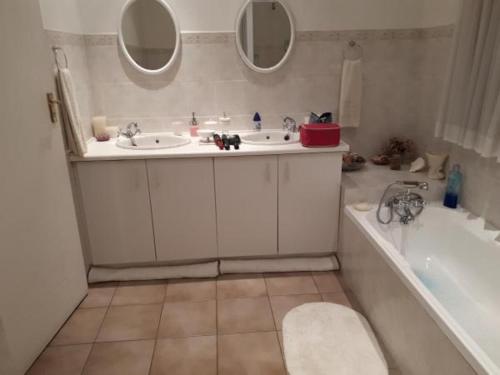 a bathroom with two sinks and a tub and two mirrors at Bougain Villa Guesthouse in Prince Albert
