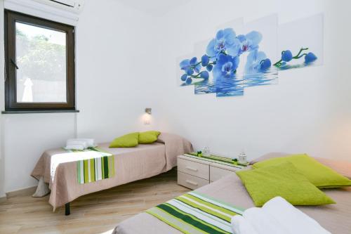 a bedroom with two beds and a painting on the wall at Il Profumo di Capri in Massa Lubrense