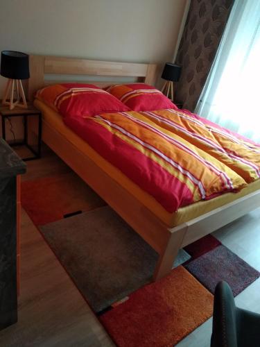 a bedroom with a bed with a red and yellow comforter at Apartmán ALEX in Poprad