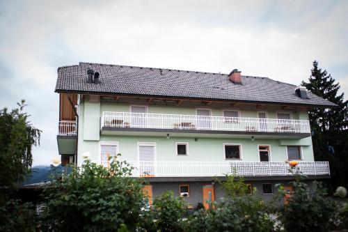 a large white building with a balcony and trees at Gostilna in Prenočišča Ferlič in Braslovče