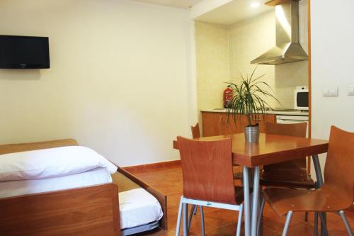 シエラネバダにあるApartamentos Montegorbeaのテーブルとベッド1台付きの部屋、キッチンが備わるアパートメントです。