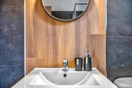 La salle de bains est pourvue d'un lavabo blanc et d'un miroir. dans l'établissement Oceania House with sea view, à Áno Sýros