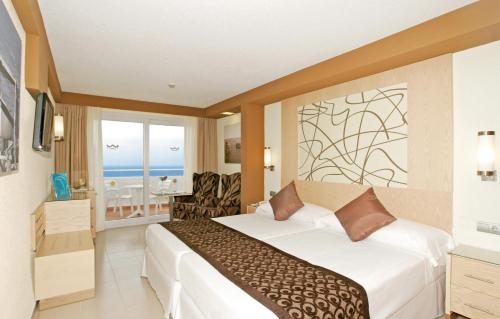 a hotel room with a bed and a view of the ocean at Riu La Mola in Playa Migjorn