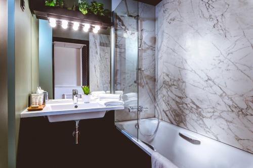 a bathroom with a sink and a shower and a tub at The ReMIX Hotel in Paris