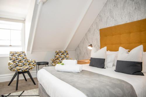 a bedroom with a large bed and a chair at Bonne Esperance Boutique Guest House in Stellenbosch