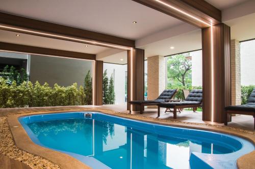 an infinity pool in a house with two chairs and a table at B Stay Hotel in Bangkok