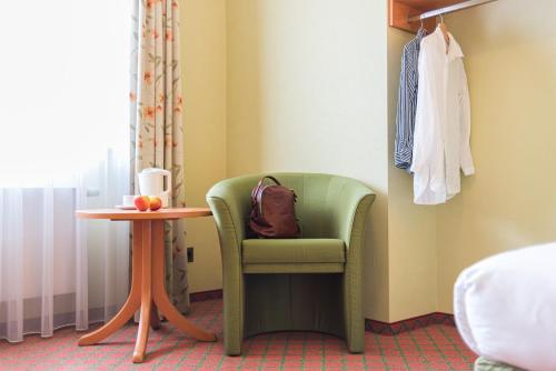 a room with a green chair and a table at Lohmann's Kapeller Hof in Langenfeld