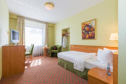 a hotel room with a bed and a television at Lohmann's Kapeller Hof in Langenfeld