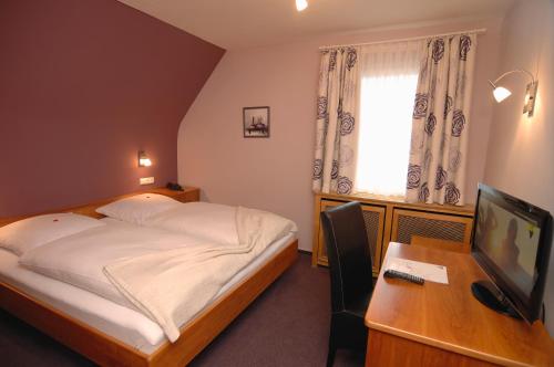 a bedroom with a bed and a desk with a television at Gasthaus zum Ochsen in Mannheim
