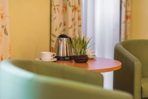 a table with a coffee maker and a plant on it at Lohmann's Kapeller Hof in Langenfeld