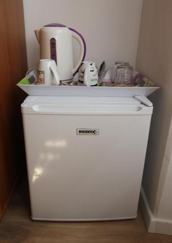 a white refrigerator with cups on top of it at Seafront rooms in Hvar