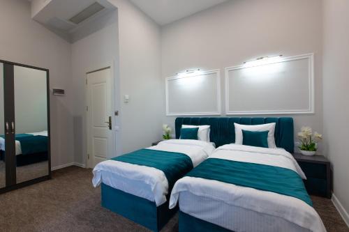 a bedroom with two beds with blue and white sheets at Royal Inn in Tbilisi City