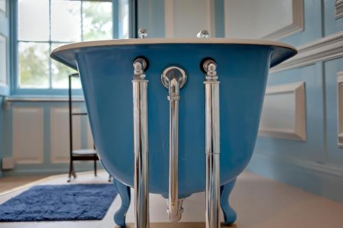 a blue bath tub in a room with a window at Kelly House Country B&B in Lifton