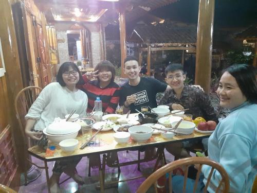 een groep mensen die rond een tafel zitten bij MeoVac Ethnic Homes in Mèo Vạc