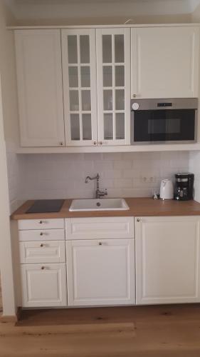 een keuken met witte kasten, een wastafel en een magnetron bij Alte Seifensiederei zu Pulkau Ferienwohnung in Pulkau