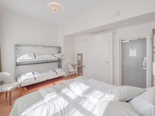 a white bedroom with two beds and a mirror at Hamnhotellet in Västervik