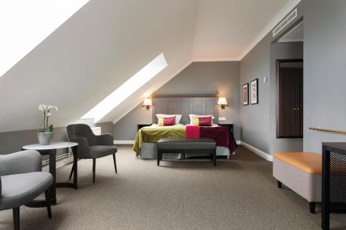 a bedroom with a bed and chairs in a attic at Elite Stora Hotellet in Jönköping