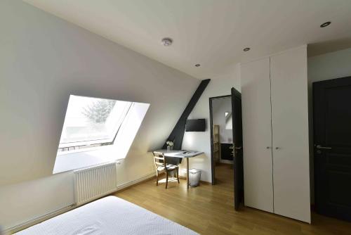 een zolderkamer met een bureau en een raam bij Ferme de Mesangeon in Beauvilliers