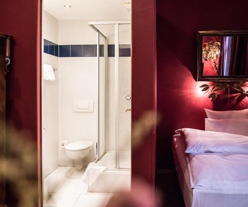 a bathroom with a bed and a toilet in a room at Hotel Ritzi in Munich