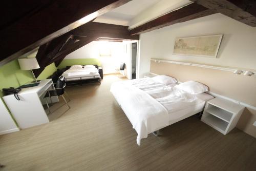 a hotel room with two beds and a desk and a bedroom at Auberge de Prangins in Prangins