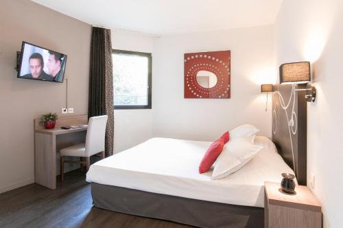 a hotel room with a bed and a desk and a television at Le Carmin by Popinns in Vitry-sur-Seine