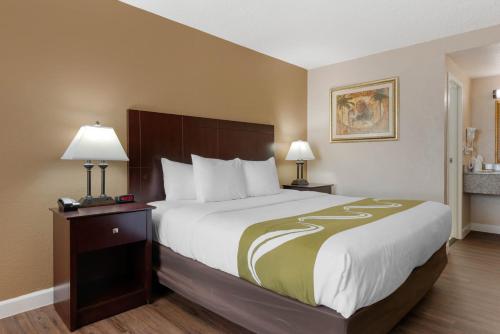 a large bed in a hotel room with two lamps at Quality Inn and Suites Conference Center in New Port Richey