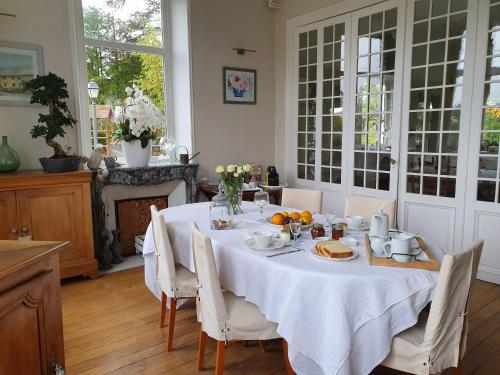 een eetkamer met een tafel met een witte tafeldoek bij Chambres d'Hôtes des Rouets in Fourmies