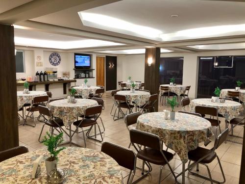 a dining room with tables and chairs and a tv at Hotel Concatto in Farroupilha