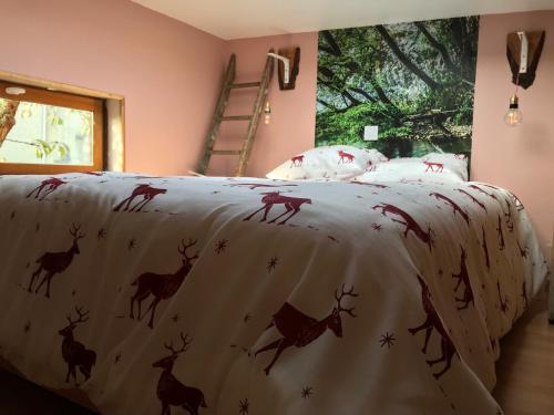 ein Bett mit einer Decke mit Hirsch drauf in der Unterkunft Cabane du hérisson in La Capelle-en-Thiérache
