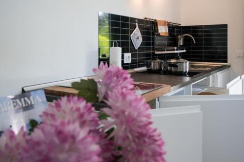 una cucina con lavandino e fiori rosa di L' Aia di Carinda R.T.A. a Grosseto