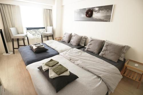 a living room with two beds and a couch at 新大阪徒步30秒 Shinosaka Station 30s, Direct to Kansai Airport 關西空港直達, Shinkansen to Kyoto, Tokyo & Nagoya, Universal Studio 16 mins, Umeda 6 mins, Kyoto 25 mins, Early Check in in Osaka