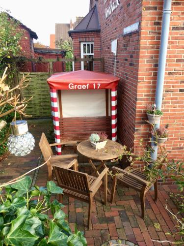 a patio with a table and chairs and a red and white booth at Hus Nordhauk in Borkum